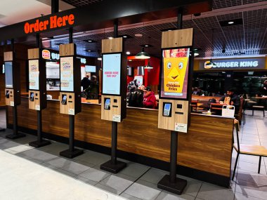 Dublin, İrlanda - 24 Ekim 2025: Dublin 'de Burger King' in içinde, müşteriler yemekten önce sipariş vermek için dokunmatik ekran kiosk kullanırlar..