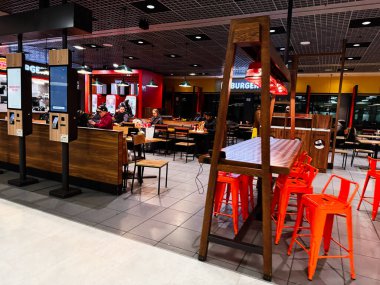 Dublin, İrlanda - 24 Ekim 2025 Dublin 'de bir fast food Burger King restoranında çalışanlar yemek hazırlarken misafirler ahşap masalarda oturur..