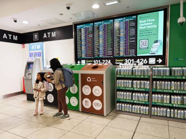 Dublin, İrlanda - 24 Ekim 2025 Dublin Havaalanı 'ndaki bir aile İrlanda yakınlarındaki büyük uçuş bilgi panolarına sahip ATM makinelerinin yanında duruyor..