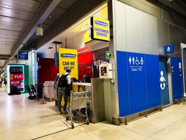 Dublin, İrlanda - 24 Ekim 2025: Dublin havaalanı terminalindeki Ryanair müşteri hizmetleri masasında gezginler kuyruğa girdi.