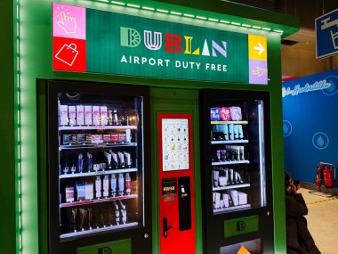 Dublin, İrlanda - 24 Ekim 2025: Parlak yeşil gümrüksüz dolaplar Dublin havaalanı terminalinde güzellik ürünleri sergiliyor, gezginleri davet ediyor.