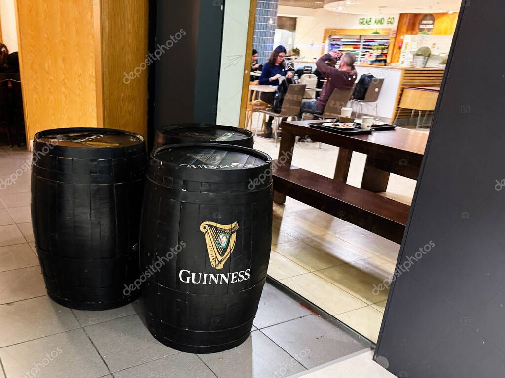 Dublin, Ireland - October 24, 2025: Dark wooden barrels outside a cafe in Dublin, Ireland, with customers enjoying drinks and conversation.