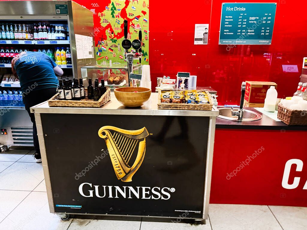 Dublin, Ireland - October 24, 2025: A Guinness branded cart displays snacks, bottles, and drink menu inside a bright red shop in Dublin