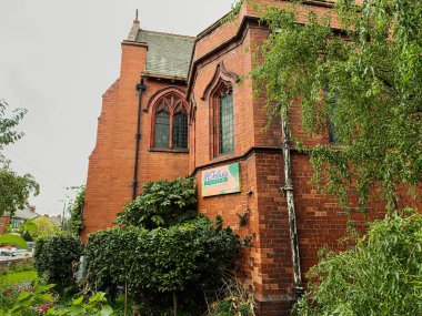 Manchester, İngiltere - 30 Eylül 2025 Manchester 'da St. Johns işareti olan ağaçlar ve yeşilliklerle çevrili bir kırmızı tuğla kilise.