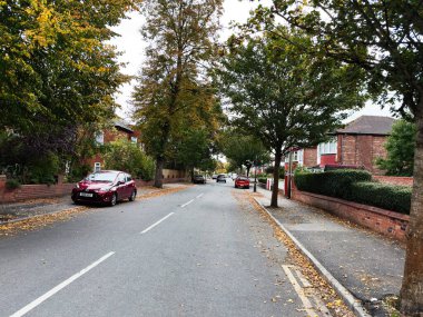 Manchester, İngiltere - 30 Eylül 2025 Manchester 'da yapraklarını döken ağaçlar ve park halindeki arabalarla dolu sessiz bir yerleşim yeri.