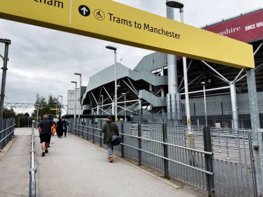 Manchester, İngiltere - 30 Eylül 2025: Yayalar modern Manchester sitesinde tramvay erişimine doğru bir patika boyunca yürürler.