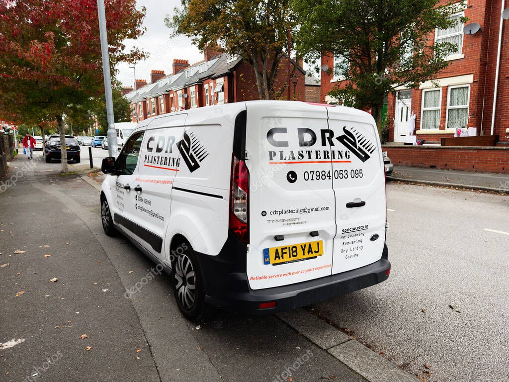 Manchester, UK - September 30, 2025: White plastering Ford Transit van on a residential street in Manchester displays branding and contact information.