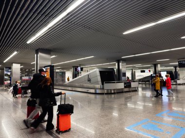 Balice, Polonya - Ekim 04, 2025: Krakow 'da yolcu ve bagajları Polonya' daki bagaj atlıkarıncasında gösteren yoğun terminal sahnesi.
