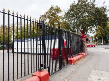 Manchester, İngiltere - 30 Eylül 2025: Siyah demir çit, bilet konteynırı, kırmızı banklar ve Manchester caddesi boyunca sonbahar ağaçları.