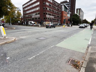 Manchester, İngiltere - 30 Eylül 2025: Manchester kentsel sokak sahnesi tuğla akademi binaları bisiklet şeridi ve hareket halindeki trafik