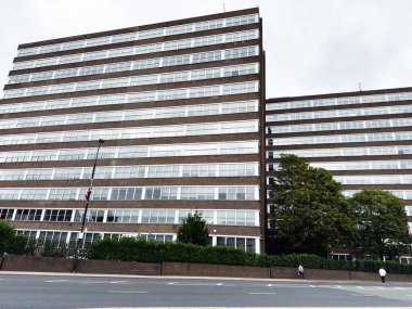 Manchester, İngiltere - 30 Eylül 2025: Manchester 'da ağaçlar, yayalar ve bir şehir sokak manzaralı büyük tuğla ofis binası.