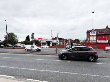 Manchester, İngiltere - 30 Eylül 2025: Manchester, İngiltere 'de sokak manzarası, tuğla dükkanları boyunca trafik, arabalar, dükkanlar ve vatansever bayrakların yer aldığı.