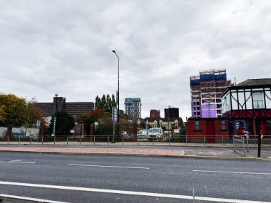 Manchester, İngiltere - 30 Eylül 2025: Manchester 'da şehir caddesi kırmızı tuğla duvarın yanında yeni binalar ve inşaatı gösteriyor.
