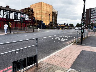 Manchester, İngiltere - 30 Eylül 2025: Manchester, İngiltere 'de altın cam bina, bar, yayalar ve işlek sokak trafiğinin yer aldığı şehir manzarası.