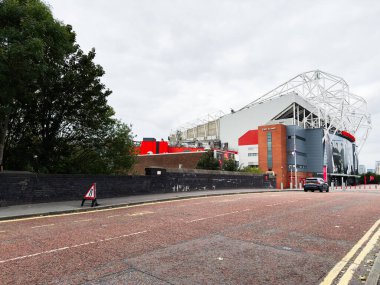 Manchester, İngiltere - 30 Eylül 2025: Manchester 'da kırmızı tuğlalı, beyaz iskeletli ve şehir manzaralı büyük bir stadyum.