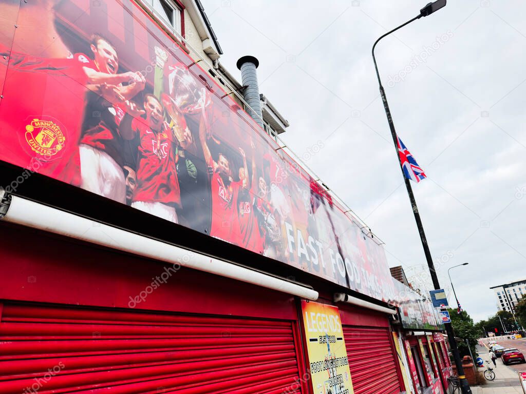 Manchester, UK - September 30, 2025: Vibrant red storefront shows Manchester United banner, cheering fans, and Union Jack flag in Manchester, UK.