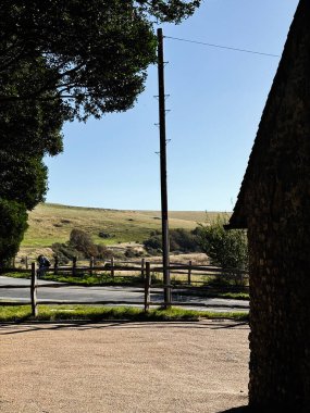 Ahşap çitleri, uzun bir elektrik direği ve Doğu Sussex 'teki çimenli tepelerin üzerinde açık mavi bir gökyüzü olan açık bir kırsal bölge..