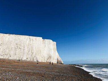Doğu Sussex, İngiltere 'deki Seven Sisters' daki görkemli tebeşir kayalıkları çakıllı plaj ve mavi deniz boyunca.