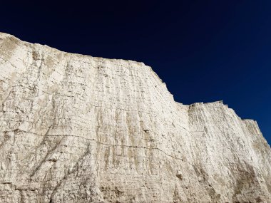 Tebeşir kayalıkları Doğu Sussex 'teki Yedi Kız Kardeş kıyılarında yükseliyor. Derin mavi bir gökyüzü ve dramatik bir ışık altında..