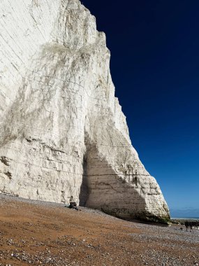 Yükselen tebeşir kayalıkları alçak gelgitte masmavi bir gökyüzünün altında çakıllı bir sahile bakar..
