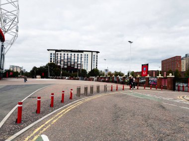 Manchester, İngiltere - 30 Eylül 2025: Manchester 'da bir stadyum girişi, kırmızı kalınlar ve modern mimariyi gösteren şehir sahnesi.