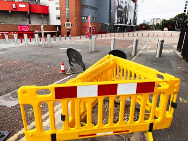 Manchester, İngiltere - 30 Eylül 2025: Manchester kentsel cadde kapanışı Parlak sarı bariyer ve güvenlik ekipmanları bir stadyum yakınında.