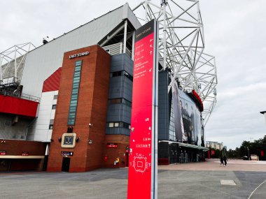 Manchester, İngiltere - 30 Eylül 2025: Manchester Stadyumu 'nun dış görünüşü kırmızı pankart, tuğla kule ve modern tabela ile.