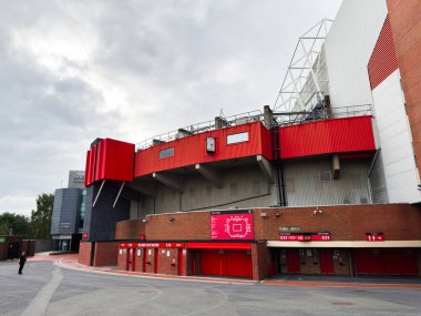 Manchester, İngiltere - 30 Eylül 2025: Manchester 'da kırmızı paneller ve tuğla işleri, tabela ve yürüyüş yollarının yer aldığı çarpıcı bir stadyum.