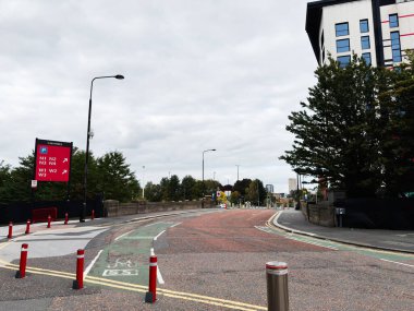 Manchester, İngiltere - 30 Eylül 2025: Manchester 'da bisiklet yolu, tabela ve modern binaları gösteren hareketli bir şehir caddesi.