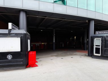 Manchester, İngiltere - 30 Eylül 2025: Tarihsel Manchester arenası dışında siyah bilet gişeleri, kırmızı kalabalık bariyerleri ve modern cam mimarisi yer alıyor.