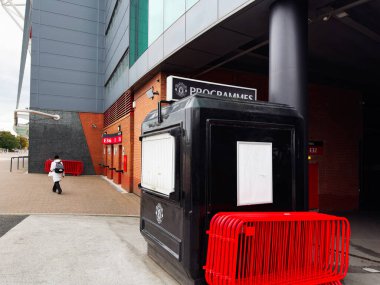 Manchester, İngiltere - 30 Eylül 2025: Manchester, İngiltere 'de siyah büfe, kırmızı bariyerler, tuğla duvarlar ve kentsel çevre ile modern arena dış görünüşü.