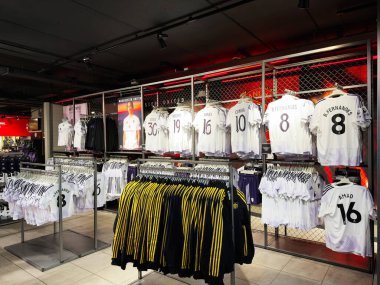 Manchester, İngiltere - 30 Eylül 2025: Beyaz Manchester United formaları parlak bir spor giyim mağazasında raflarda ve askılarda.
