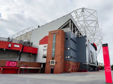 Manchester, İngiltere - 30 Eylül 2025: Manchester 'da tuğla kulesi ve çelik iskeleti olan bir futbol stadyumunun modern dış görünüşü.