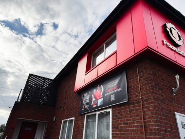 Manchester, İngiltere - 30 Eylül 2025: Manchester 'daki bir vakıf binasının dış görünümü, kırmızı paneller, tuğla duvarlar ve promosyon afişi.