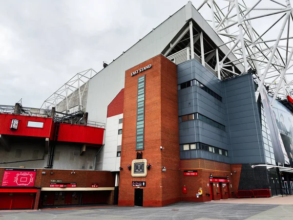 Manchester, İngiltere - 30 Eylül 2025: Tuğla kule, mavi paneller ve kırmızı aksanlı büyük Manchester stadyumunun dış görünümü.