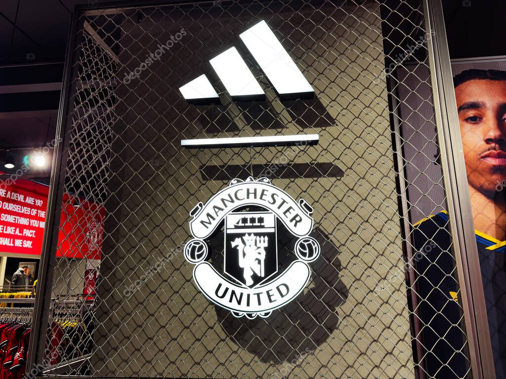 Manchester, UK - September 30, 2025: Manchester shop window display featuring the club logo behind mesh fencing and clothing on shelves.
