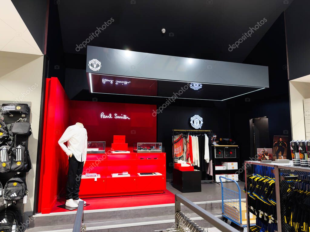 Manchester, UK - September 30, 2025: Manchester United store interior featuring red display shelves, mannequins, and clothing on racks.
