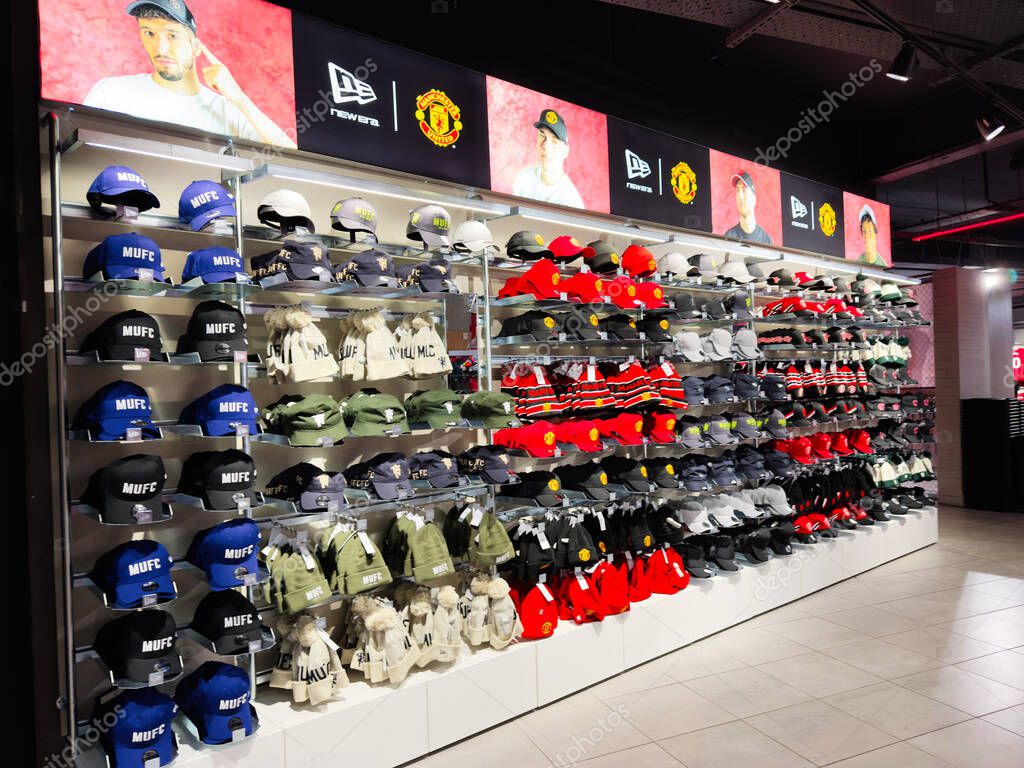 Manchester, UK - September 30, 2025: A wall of blue, black, red, and white MUFC hats in a modern retail showroom in Manchester, UK.