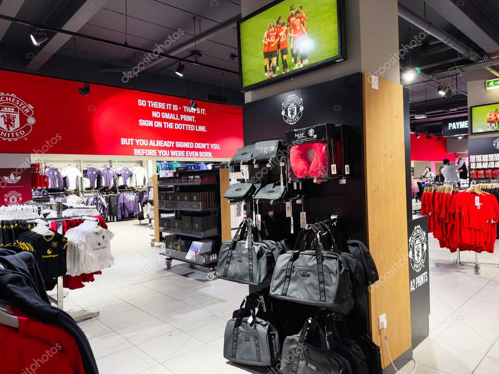 Manchester, UK - September 30, 2025: Interior view of a Manchester store with red apparel, bags and branded merchandise on display.