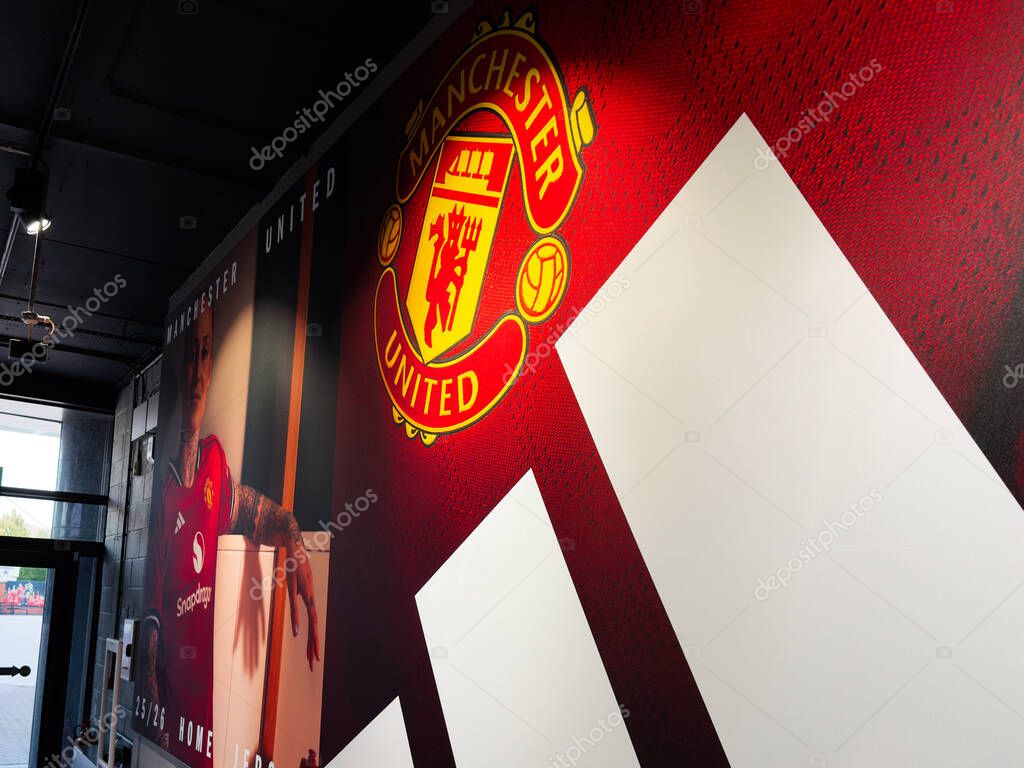 Manchester, UK - September 30, 2025: Interior view featuring Manchester United crest, red backdrop, and large white shapes in a modern gallery corridor.