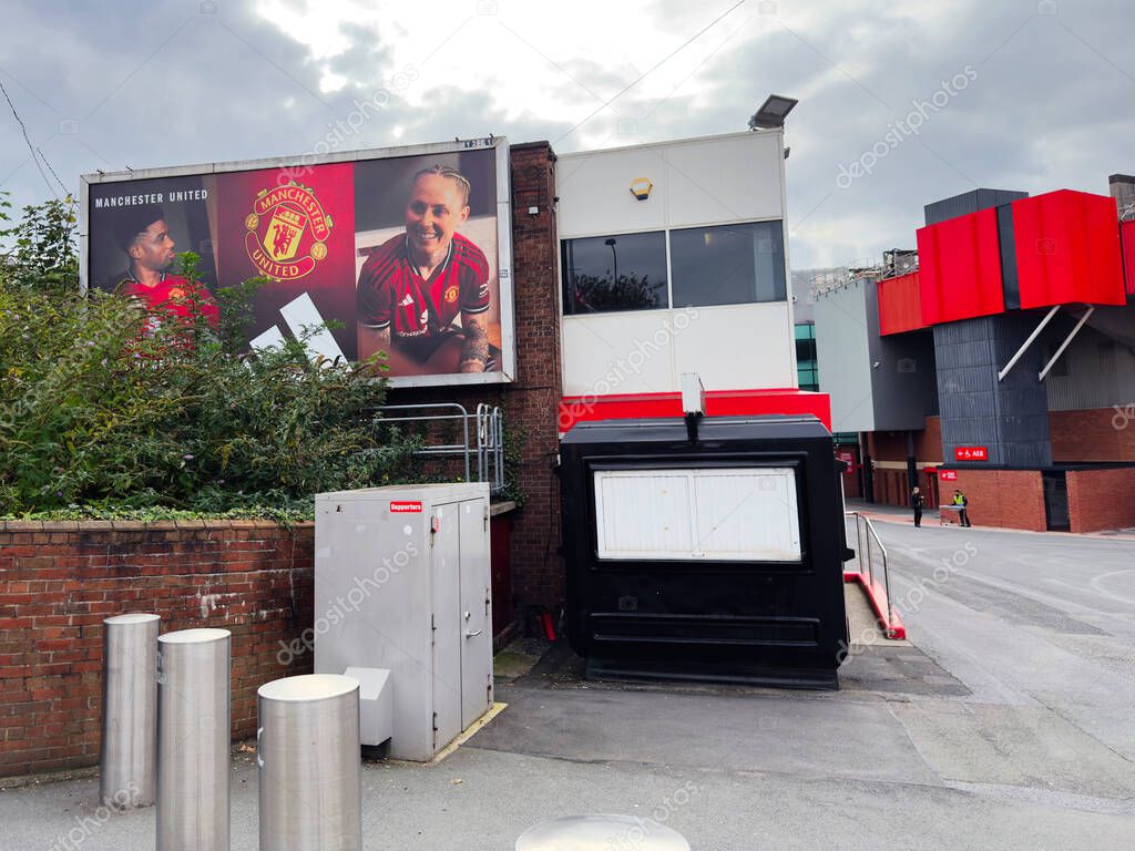 Manchester, UK - September 30, 2025: A street level scene in Manchester with a big billboard beside contemporary buildings and red accents.