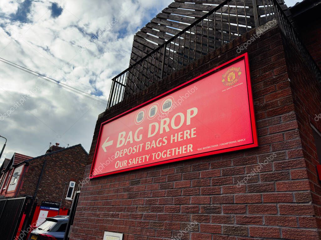 Manchester, UK - September 30, 2025: Bright red bag drop sign on brick wall outside a Manchester building inviting customers to deposit bags.