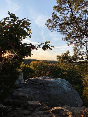 Ağaçlı kaya çıkıntısı ve Colorado Springs, Tanrıların Bahçesi 'ndeki orman vadisinde gün batımı parlıyor..