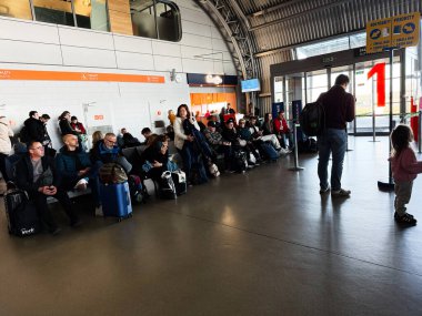 Şimdi Dwy Dwor Mazowiecki, Polonya - 22 Ekim 2025: Gezginler ve bagaj hattı modern bir havaalanı terminalindeki oturma alanı, çeşitli bir kuyruk ve seyahat ruh halini gösteriyor.