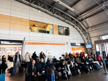 Şimdi Dwy Dwor Mazowiecki, Polonya - 22 Ekim 2025: Gezginler yoğun bir havaalanı salonunda bavullarıyla oturur, kalkış ve bağlantı beklerler.
