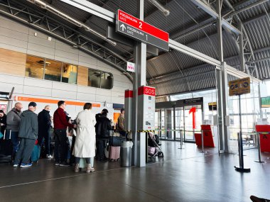 Şimdi Dwy Dwor Mazowiecki, Polonya - 22 Ekim 2025: Yolcular, Polonya 'nın Modlin Havaalanı' ndaki modern bir havaalanı terminalinde bavullarıyla bekliyor.