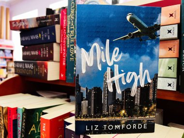 Kyiv, Ukrayna - 10 Kasım 2025: Şehir silueti arkaplanına karşı cesur bir Mile High 'ın yer aldığı renkli bir kitapçı sergisi.