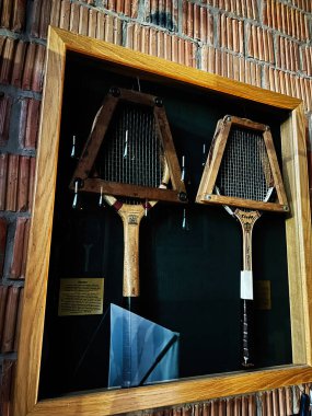 Kyiv, Ukrayna - 10 Kasım 2025: Vintage ahşap Wisden Kupası raketleri tuğla bir duvara karşı cam bir kutuda sergileniyor, müze tarzı spor dekorasyonu.