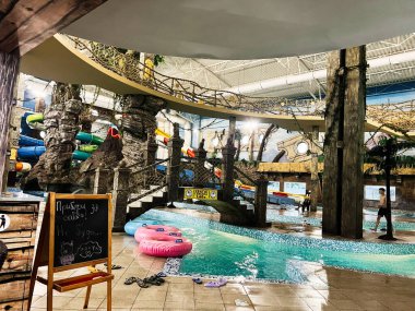 Khmelnytsky, Ukrayna - 10 Kasım 2025: Taş sütunları, sarmal kaydırakları ve renkli boruları olan hareketli bir kapalı su kompleksi.