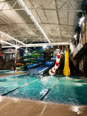 Khmelnytsky, Ukrayna - 10 Kasım 2025: Aile eğlencesi için slaytlar ve parlak havuzlarla dolu canlı kapalı su parkı sahnesi.